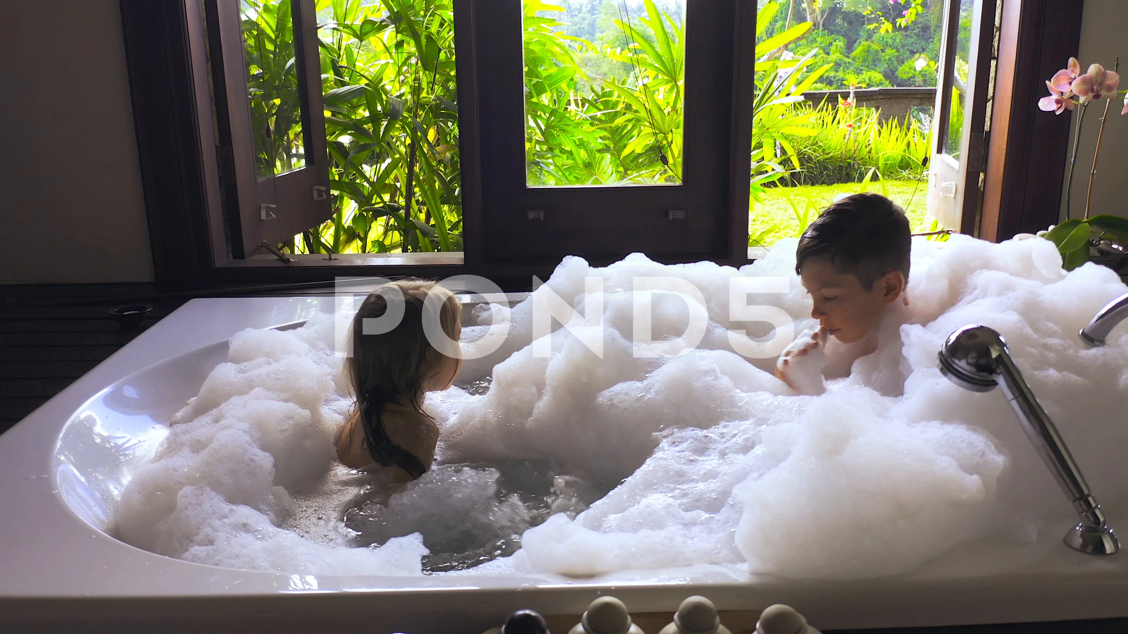 Brother and sister playing with foam in the bathroom. Concept of happy family and childhood.