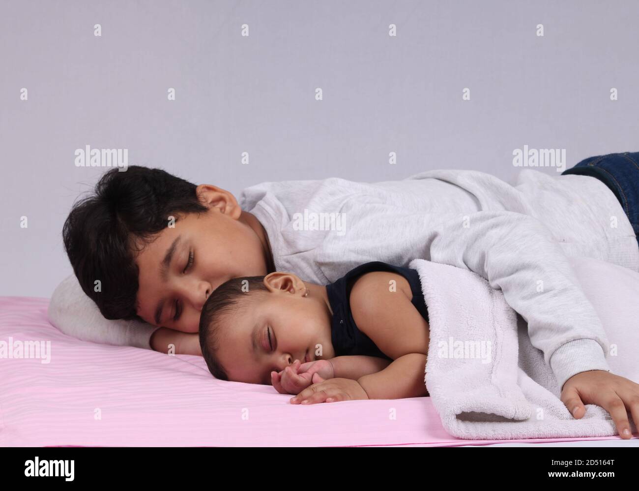 Cute little siblings peacefully sleeping together while holding the hands of each other