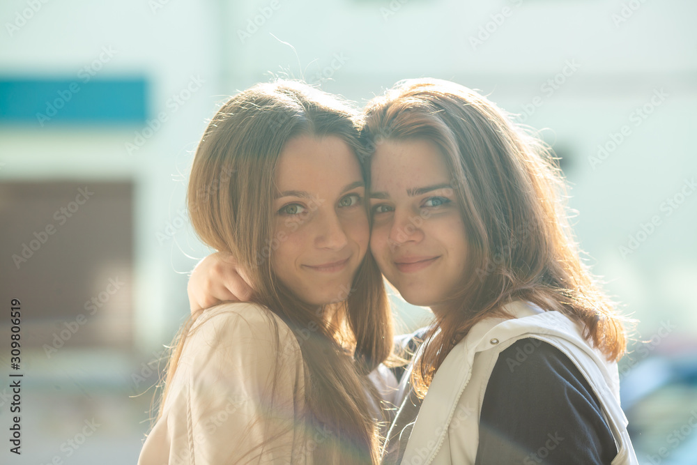 Two young sweet girls on a bed in bright bedroom. Lesbian couple