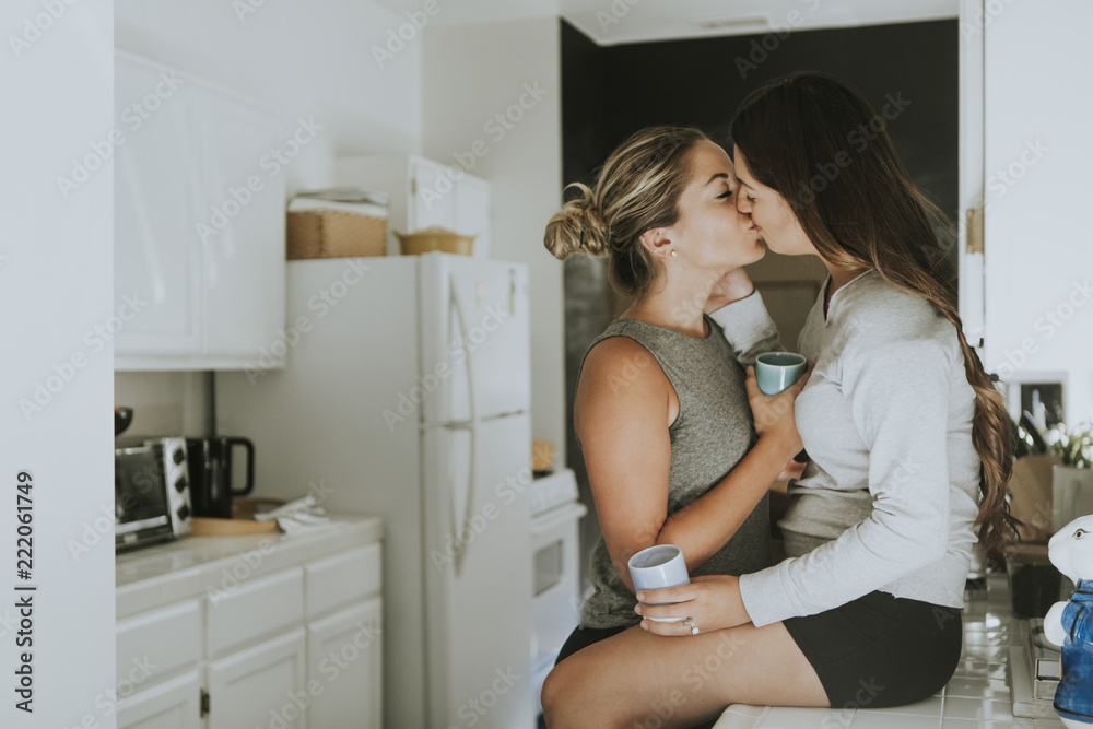 Portrait of confident happy lesbians sitting at table in kitchen